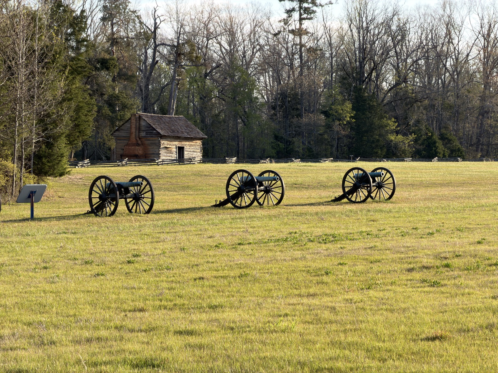 Three field guns in line behind a split-rail fence, with an interpretive marker at the left, Shiloh National Military Park.